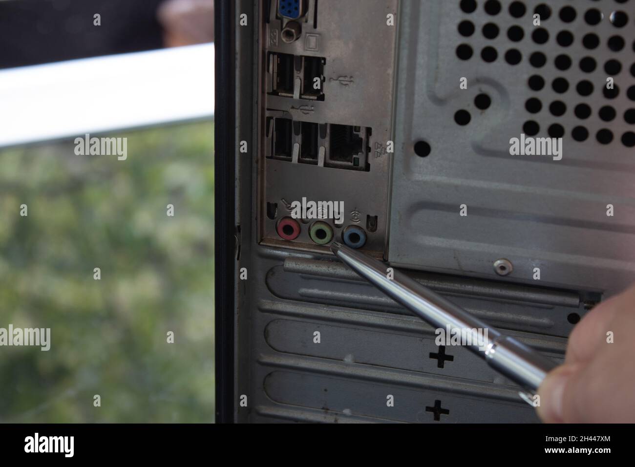 Mit einem silbernen Kugelschreiber auf die hinteren Anschlüsse eines Heimcomputers zeigen. Stockfoto