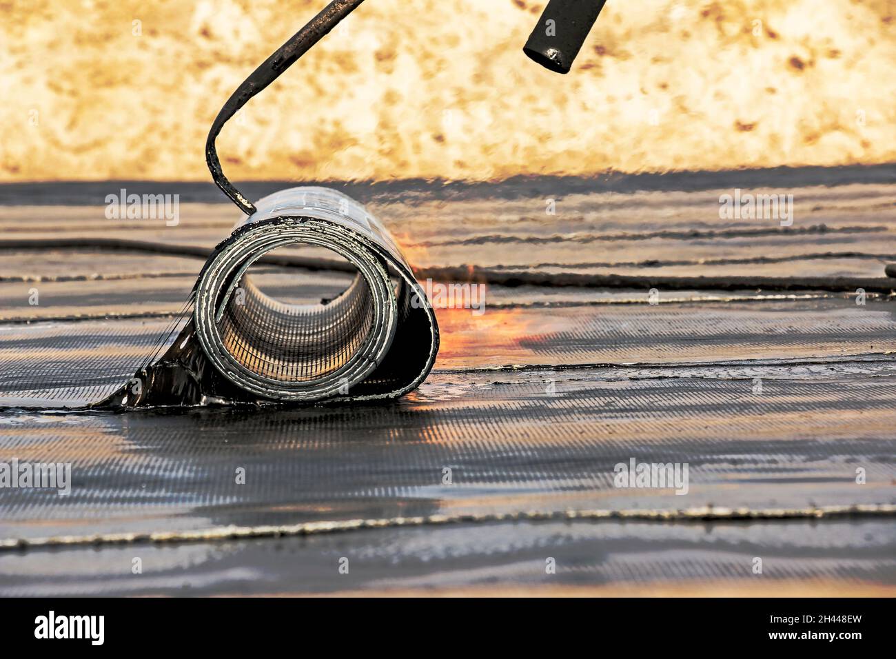Der Prozess der Installation von Dachmaterial mit einem Lötbrenner. Der bituminöse Filz schmilzt während des Installationsprozesses. Weiches Dach. Stockfoto