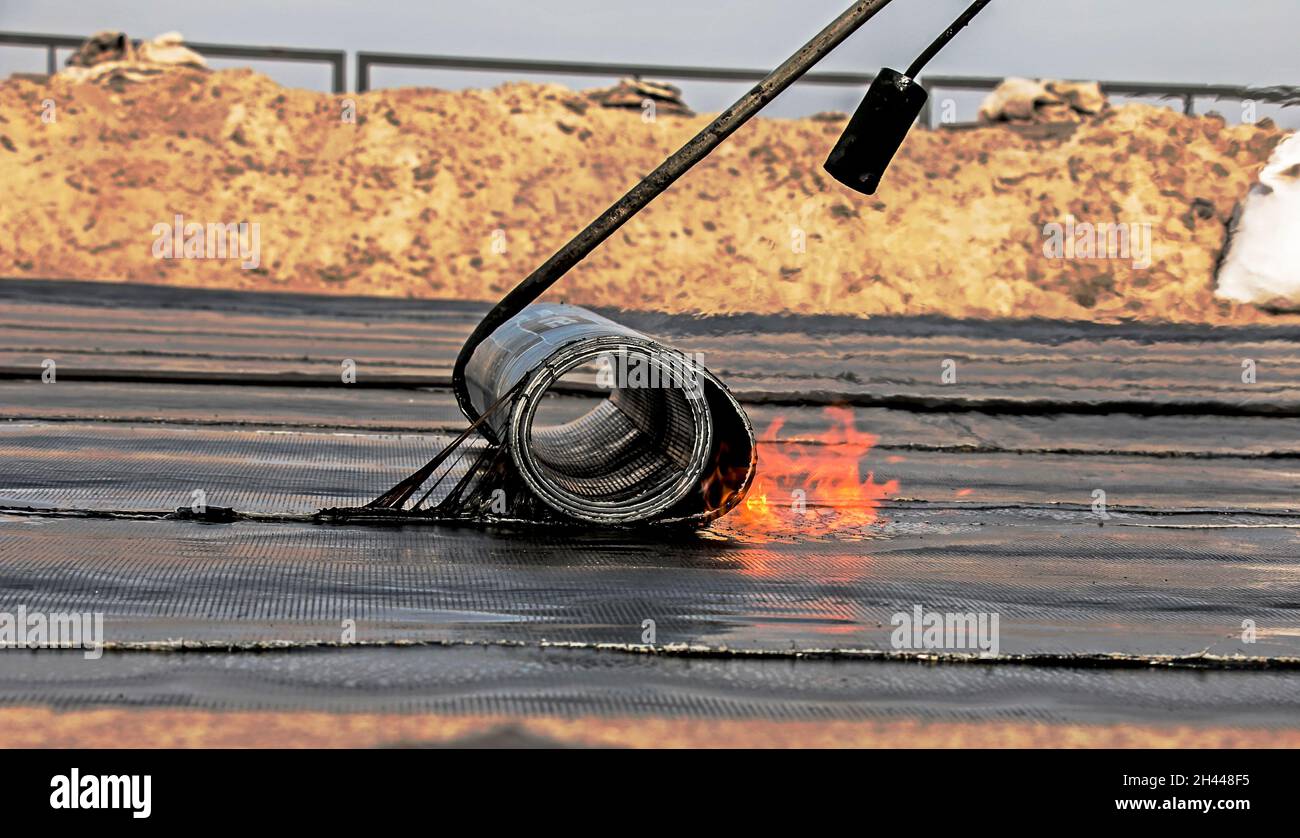 Der Prozess der Installation von Dachmaterial mit einem Lötbrenner. Der bituminöse Filz schmilzt während des Installationsprozesses. Weiches Dach. Stockfoto