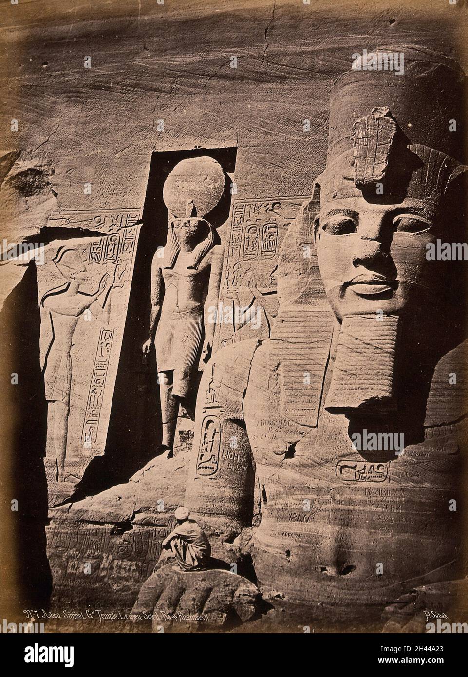 Der Abou Simbel Tempel (der Sonnentempel von Ramesses II), Nubia, Ägypten: Detail der Fassade, die Ramesses II und den sonnengott Ra zeigt; ein Mann hockt im Vordergrund, um Skala zu zeigen. Foto von Pascal Sébah, ca. 1875. Stockfoto