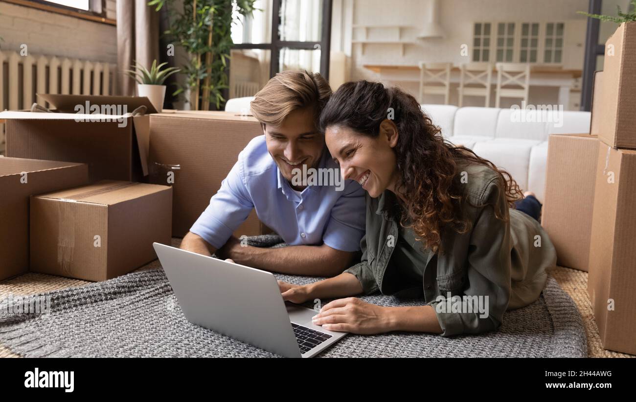 Junges Paar verwenden Laptop, um Waren online am Umzugstag zu kaufen Stockfoto