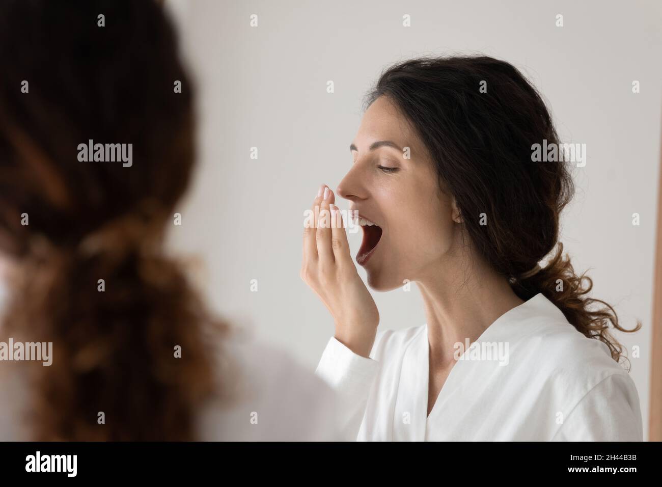 Frau bedeckt den Mund mit der Handfläche, um die Frische der Atmung zu überprüfen Stockfoto
