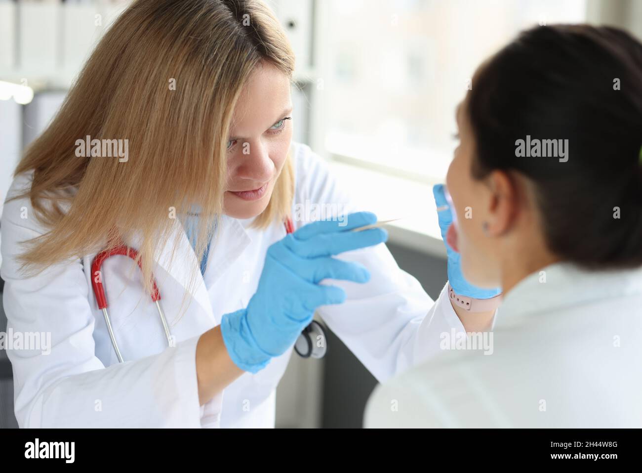 Der Arzt führt eine körperliche Untersuchung der Nahaufnahme des Kehlkopfes des Patienten durch Stockfoto