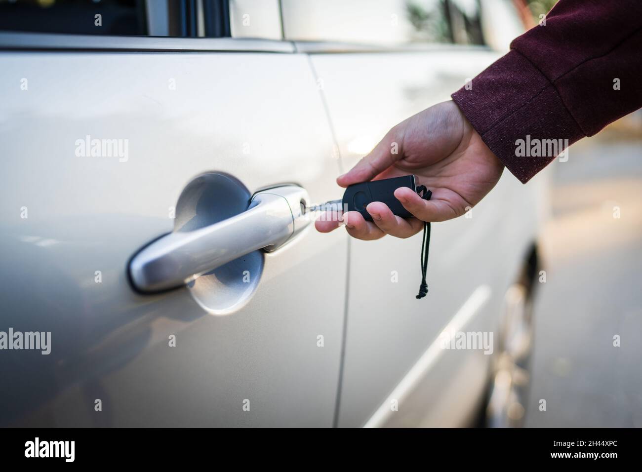 Nahaufnahme eines unbekannten kaukasischen Mannes, der die Fahrzeugtür mit den Autoschlüssel verriegelt oder entriegelt hat Stockfoto
