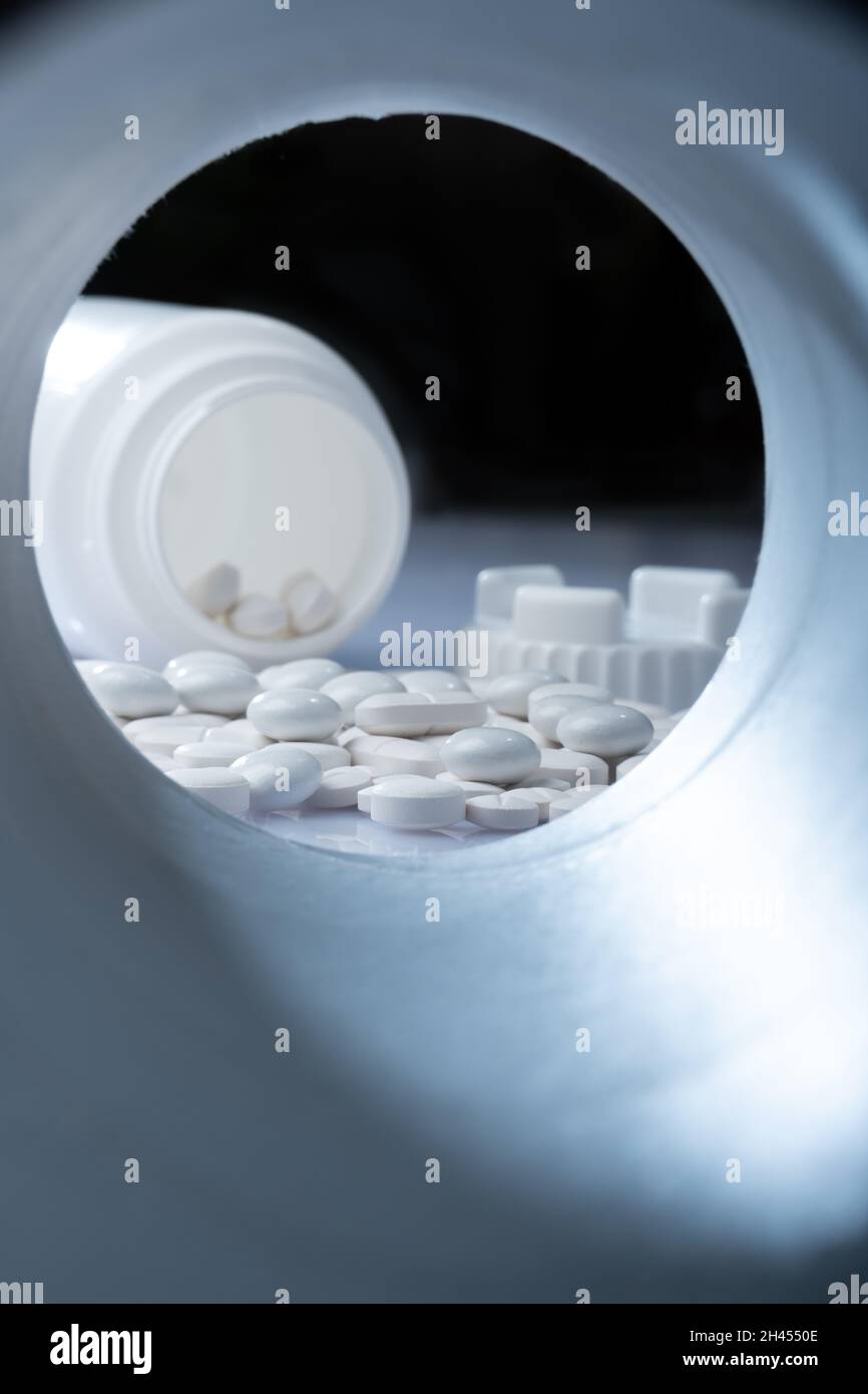 Helsinki / Finnland - 31. OKTOBER 2021:Nahaufnahme von weißen Pillen vor weißem Hintergrund mit Plastikpillenbehälter im Hintergrund Stockfoto