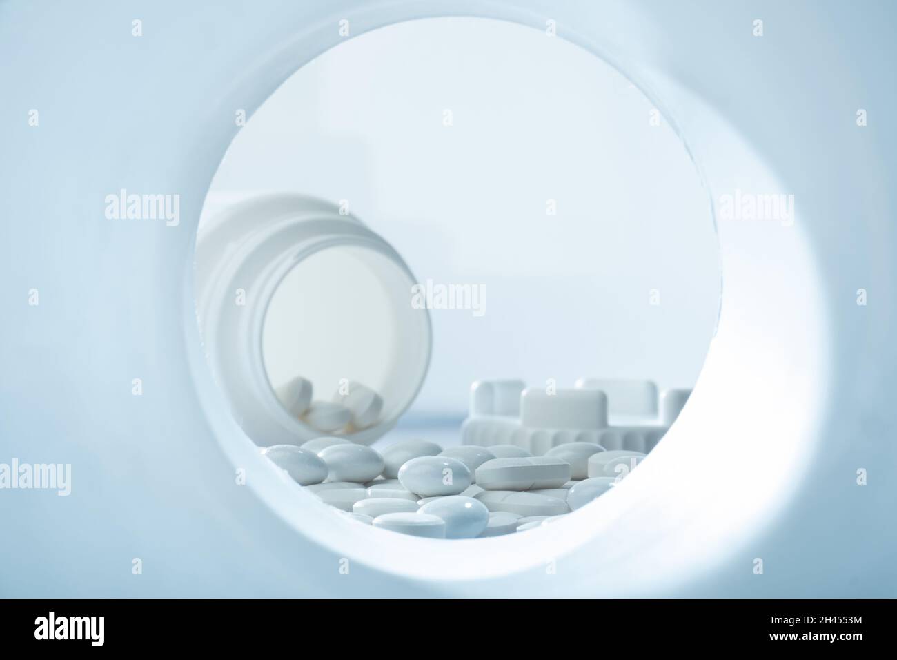 Helsinki / Finnland - 31. OKTOBER 2021:Nahaufnahme von weißen Pillen vor weißem Hintergrund mit Plastikpillenbehälter im Hintergrund Stockfoto