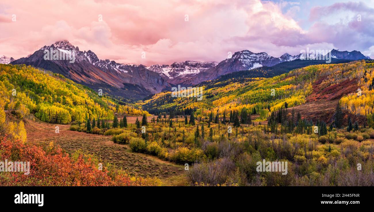 Ein farbenfrohes Tal mit der East Fork des Dallas Creek mit dramatischen Herbstfarben unter Mount Sneffels und stimmungsvollen Sonnenuntergangswolken in den San Juan Mountains. Stockfoto