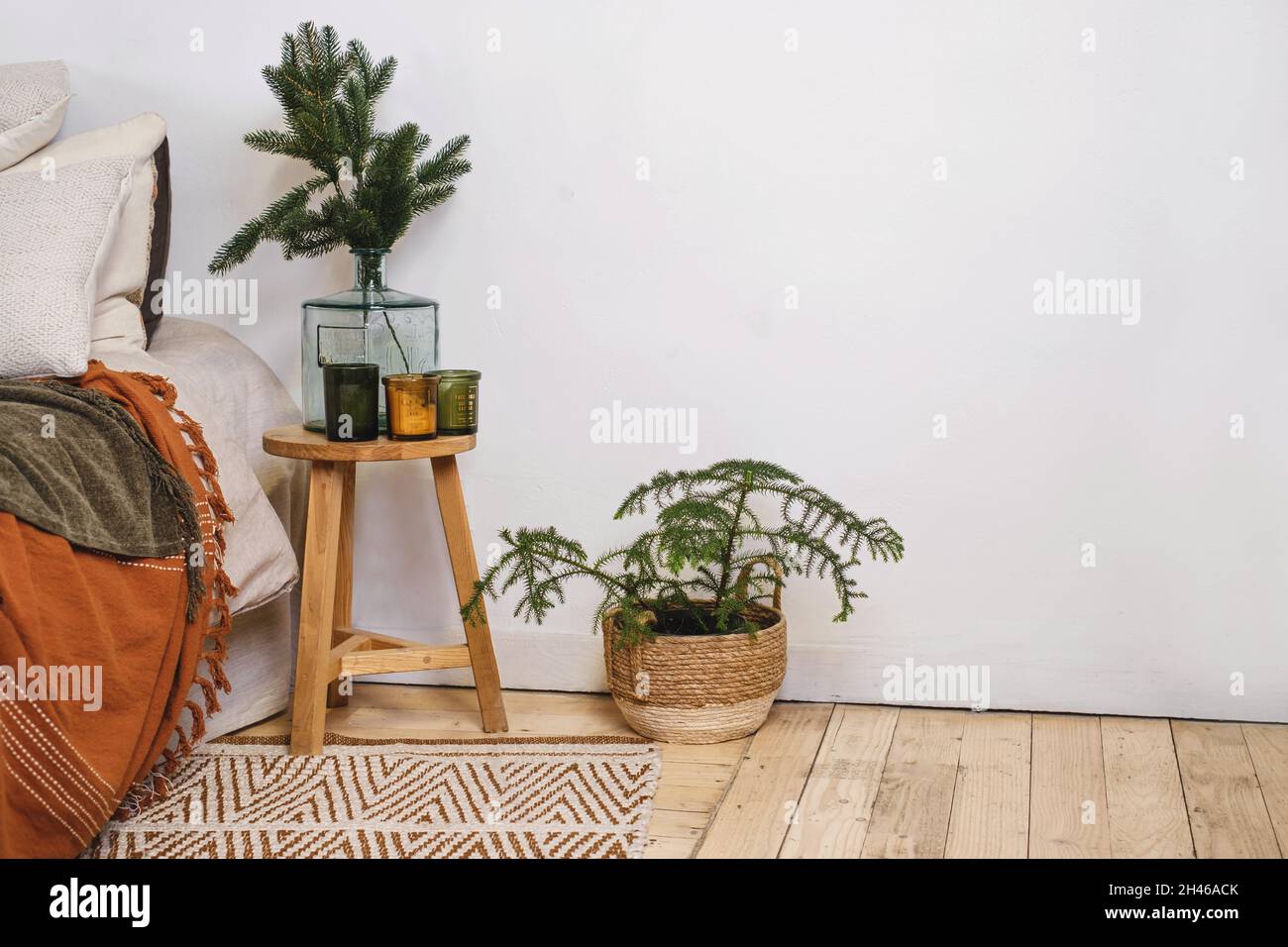 Wohnzimmer Weihnachtsdekor neben dem Bett im Öko-Stil, natürliche Elemente und echte Tanne in Topf und Zweige in Vase. Skandinavischer Stil, rustikales Heimexemplar Stockfoto