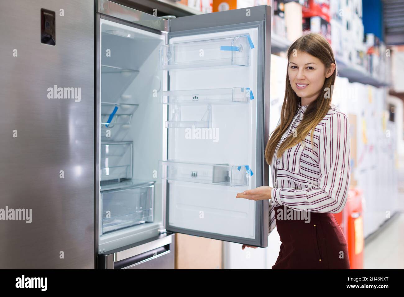 Verkäuferin zeigt Kühlschrank Stockfoto