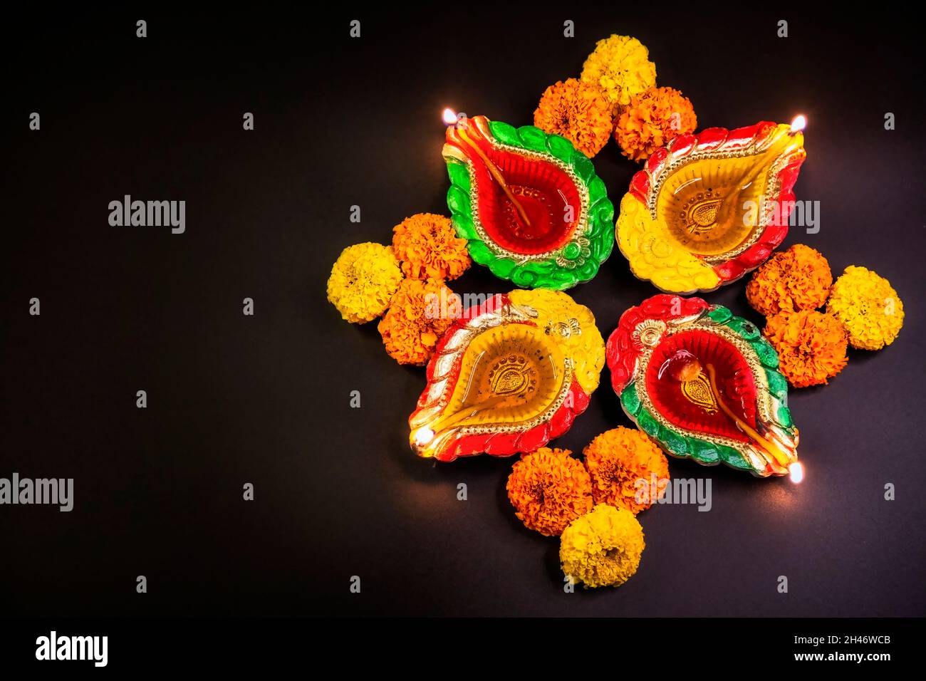 Diwali traditionelle Diya-Lampen aus Lehm, verziert mit Ringelblumen auf dunklem Hintergrund Stockfoto