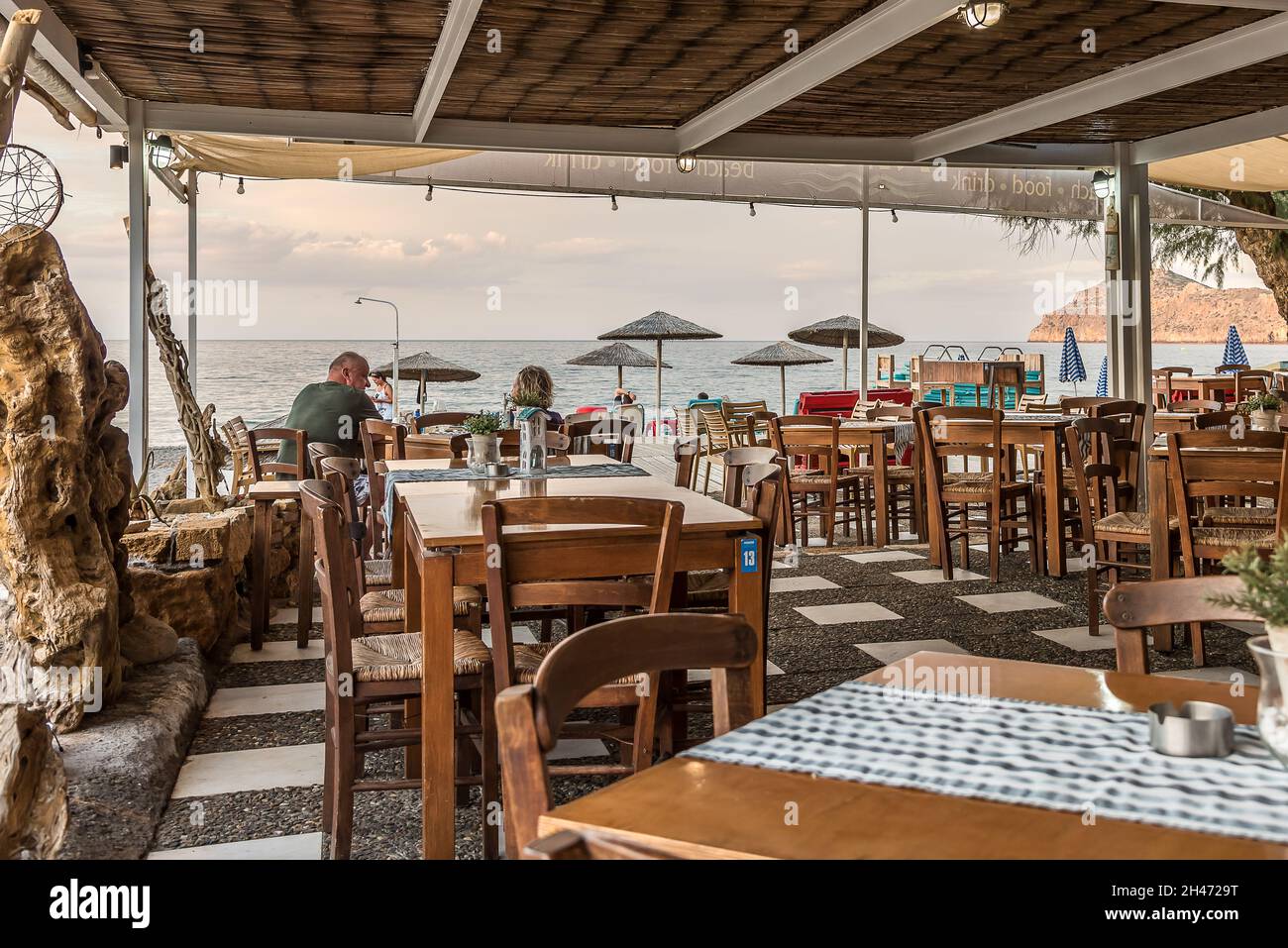 Mann und Frau sitzen an einem Tisch in einem griechischen Restaurant mit Blick auf das Meer, Platanias, Kreta, Griechenland, Oktober 7, 2021 Stockfoto