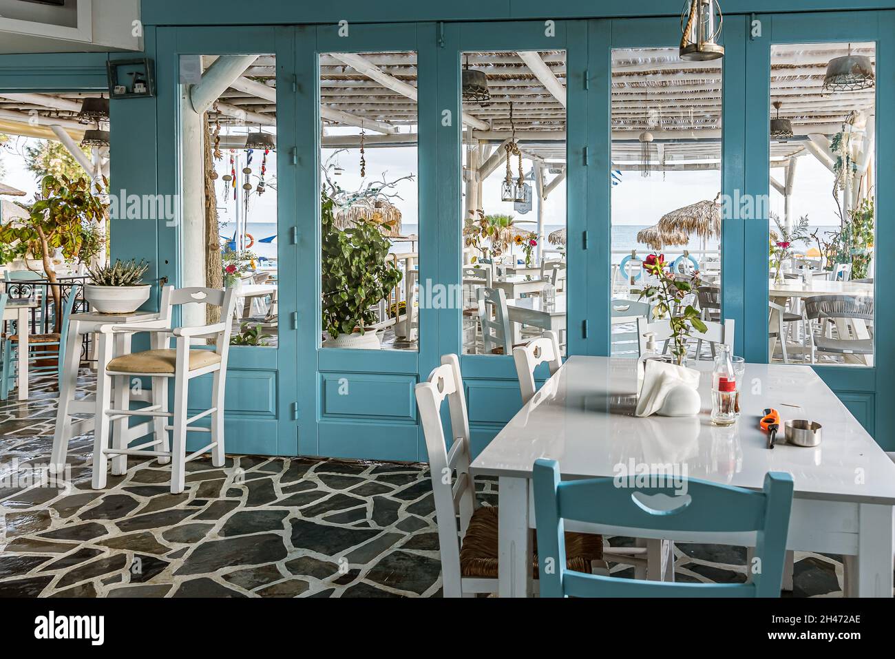 griechisches Restaurant mit blauen und weißen Tischen mit Blick auf den Strand und das blaue Mittelmeer, Platanias, Kreta, Griechenland, Oktober 7, 2021 Stockfoto