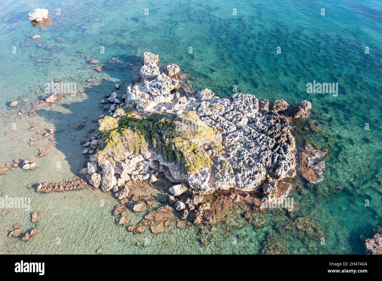Einsam großer grober Felsen in salzig klarem, transparentem türkisblauem Ägäis-Meer. Luftdrohnenaufnahme der griechischen wilden Felsformation in graubrauner Farbe w Stockfoto