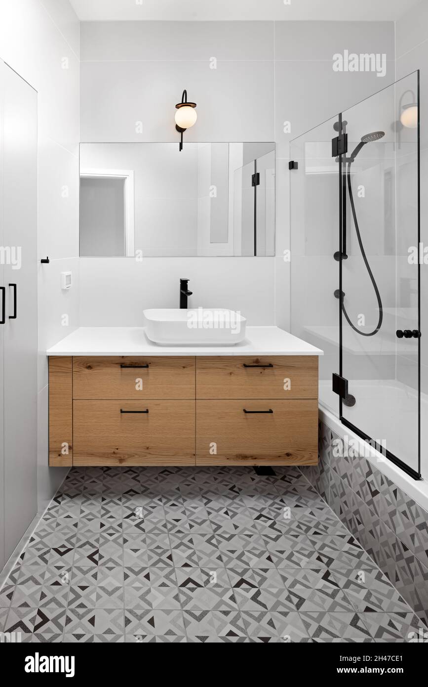 Badezimmer, brauner Holzschrank, beleuchtete Leuchte und abwechslungsreiche  Bodenfliesen Stockfotografie - Alamy