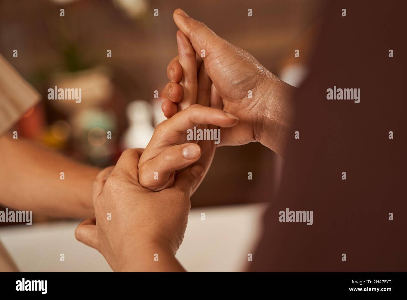 Masseuse dehnt die Finger des Kunden während der Handmassage Stockfoto