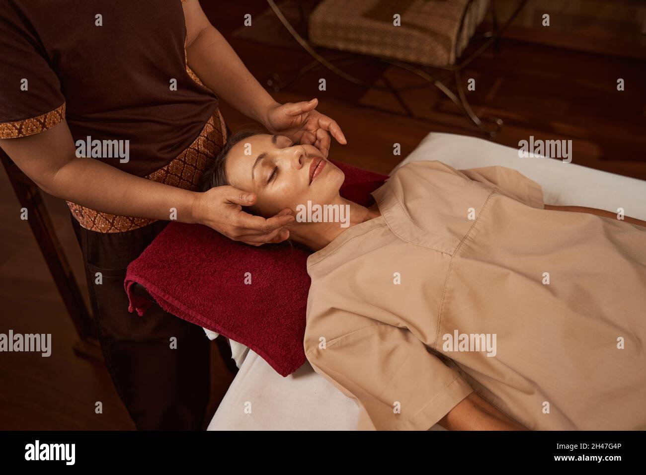 Professionelle Masseuse massiert Akupressurpunkte auf dem Gesicht des Kunden Stockfoto