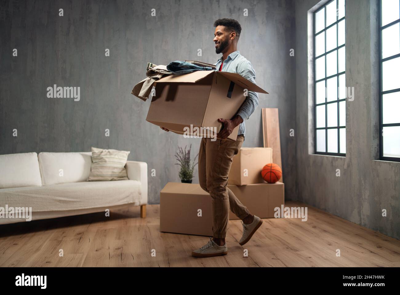 Glücklicher junger Mann mit Packkisten, Umzug nach Hause, neues Wohnkonzept. Stockfoto
