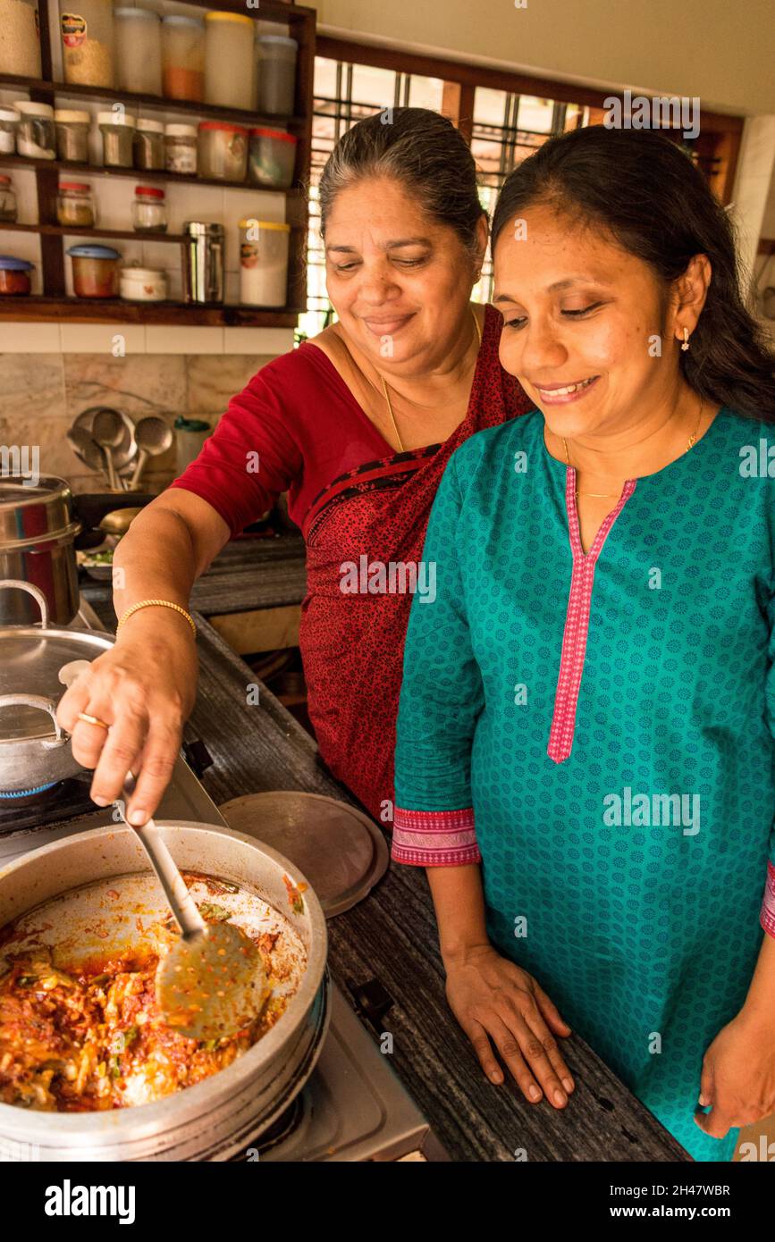 Anu Mathew und ihre Schwiegermutter, Aniamma Mathew, helfen beim Kochen in der Küche auf Philipkuttys Farm, einem luxuriösen Urlaubsort auf einem künstlichen bauernhof Stockfoto