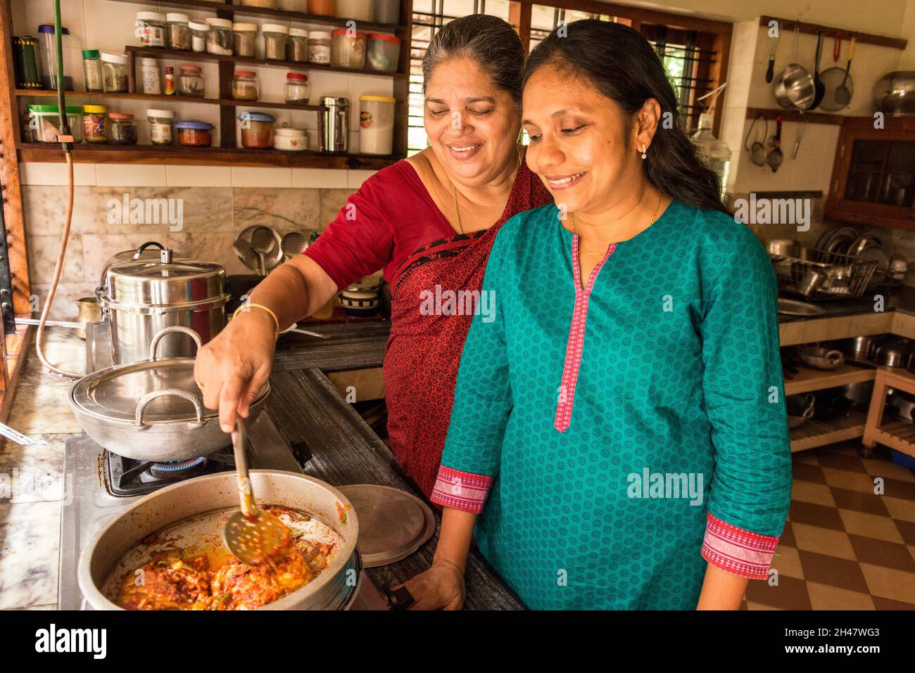 Die Besitzer Anu Mathew und ihre Schwiegermutter Aniamma Mathew helfen, die Küche auf dem familiengeführten Bauernhof von Philipkutty zu teilen, ein Luxusurlaub Stockfoto