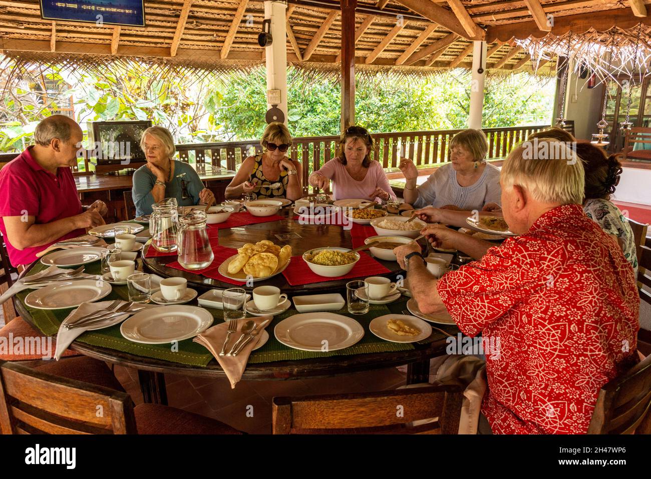 Hotelgäste sitzen an einem runden Tisch für ihr Mittagessen auf Philipkuttys Farm, einem Luxusresort auf einer künstlichen Insel Kottayam im Kerala Bac Stockfoto