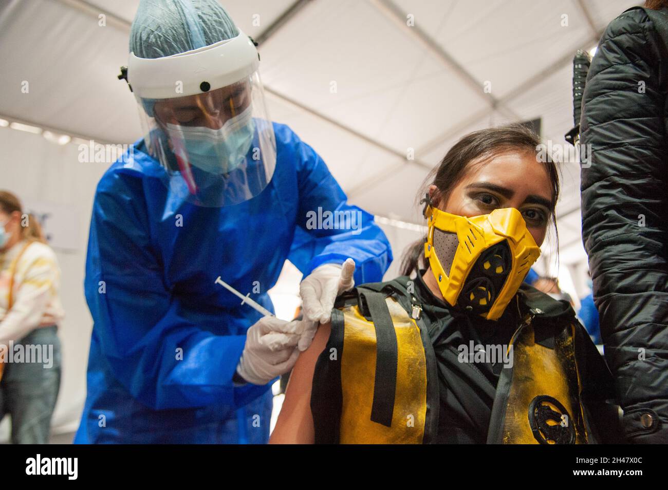 Ein Mädchen, das als Skorpion in der Gestalt des tödlichen Kampfes gekleidet ist, als sie ihre erste Dosis des Impfstoffs COVID-19 erhält, während die kolumbianische Regierung beginnt, zu impfen Stockfoto