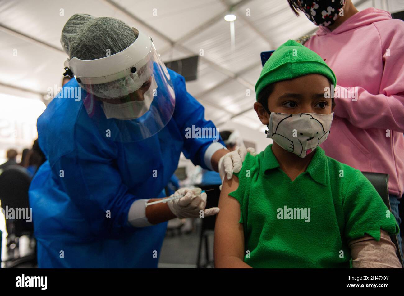Ein Kind, das an halloween ein Peter Pan Kostüm verwendet, erhält seine erste Dosis des Impfstoffs COVID-19, als die kolumbianische Regierung beginnt, Kinder zu impfen Stockfoto