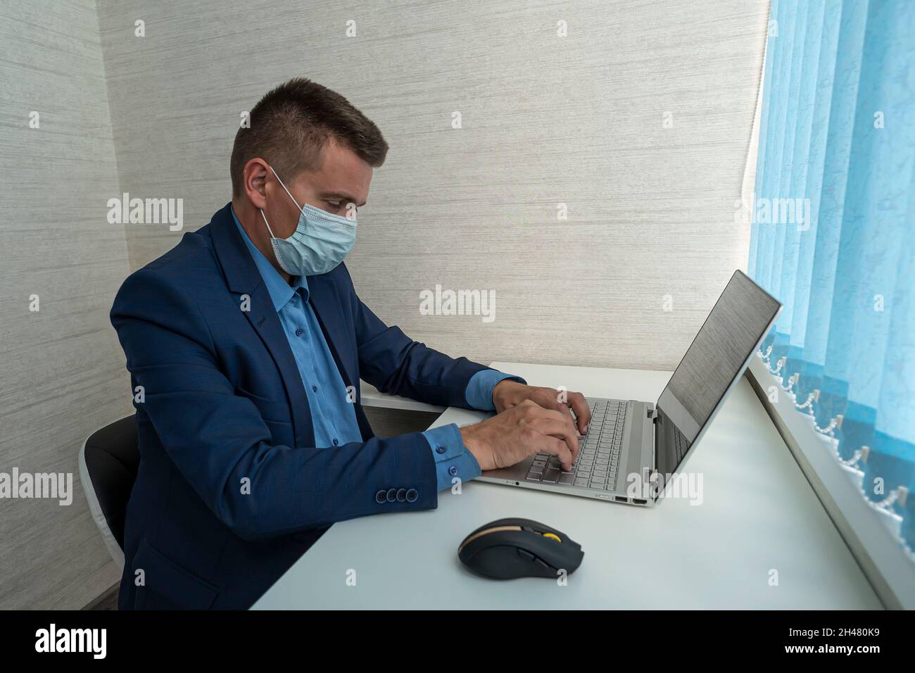 Mann mit Gesichtsmaske, der von zu Hause aus arbeitet und sich Sorgen um Covid-19, Coronavirus, soziale Distanz und Selbstisolation macht. Geschäftsmann und abgelegener Busin Stockfoto