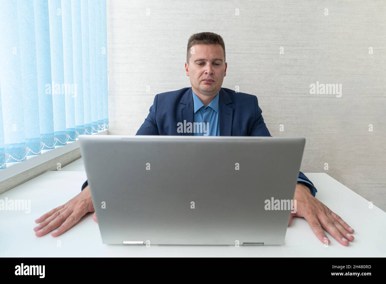 Geschäftsmann, der sich auf Computerarbeit konzentriert, auf den Laptop-Bildschirm schaut, denkt. Fokussiertes Lesen von Informationen auf einem Laptop im Büro. Der Manager Stockfoto