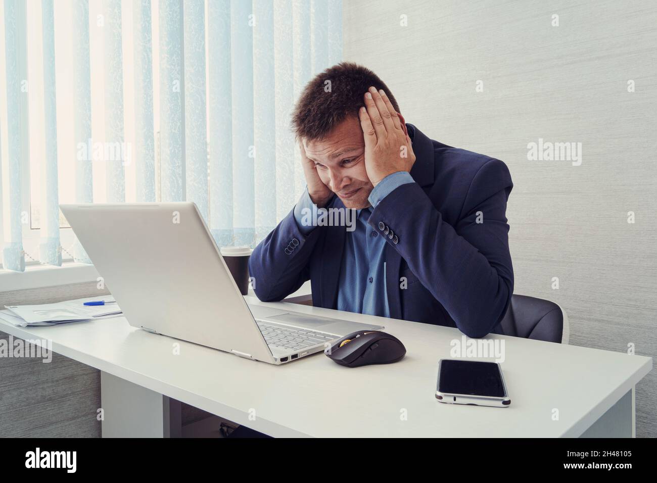 Nachdenklicher Geschäftsmann, der auf seinen Laptop schaut. Ein müder Mitarbeiter bei der Arbeit vor einem Computermonitor. Lästige Arbeit. Ein trauriger Geschäftsmann. Müde Augen Stockfoto