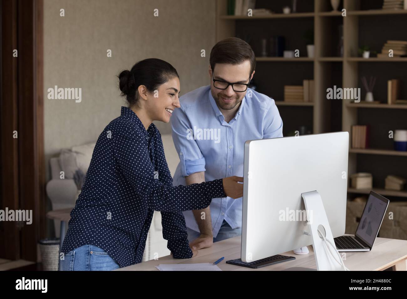 Fröhliche junge, gemischte Rennangestellte, die Computermonitor betrachten. Stockfoto