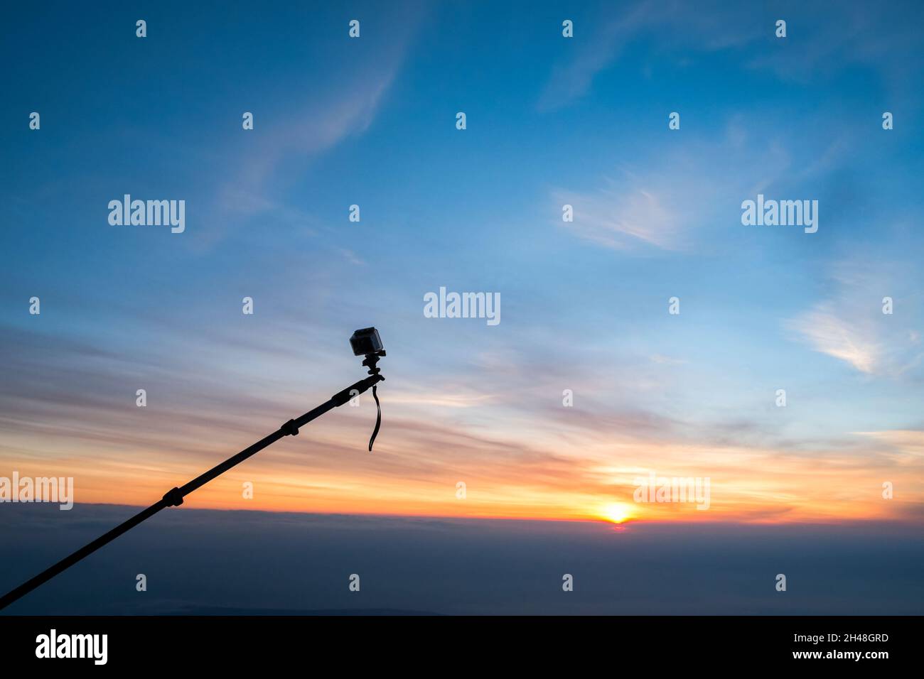 Eine GoPro Action-Sport-Kamera, die an einem Boom befestigt ist und die Anwesenheit eines Heißluftballons bei Sonnenaufgang fotografiert Stockfoto