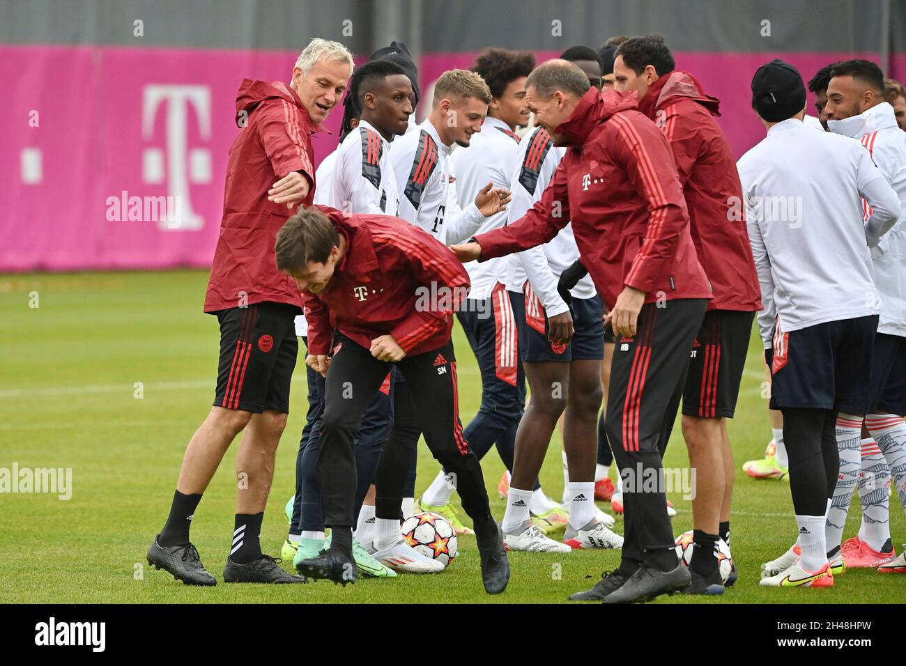 Team, die Spieler feiern den Geburtstag von Reha-Trainer Simon Martinello, der durch ein Gitter gehen muss. Fußball Champions League/FC Bayern München - SL Benfica Lisbon München, Abschlusstraining am 01.11.2021 Stockfoto