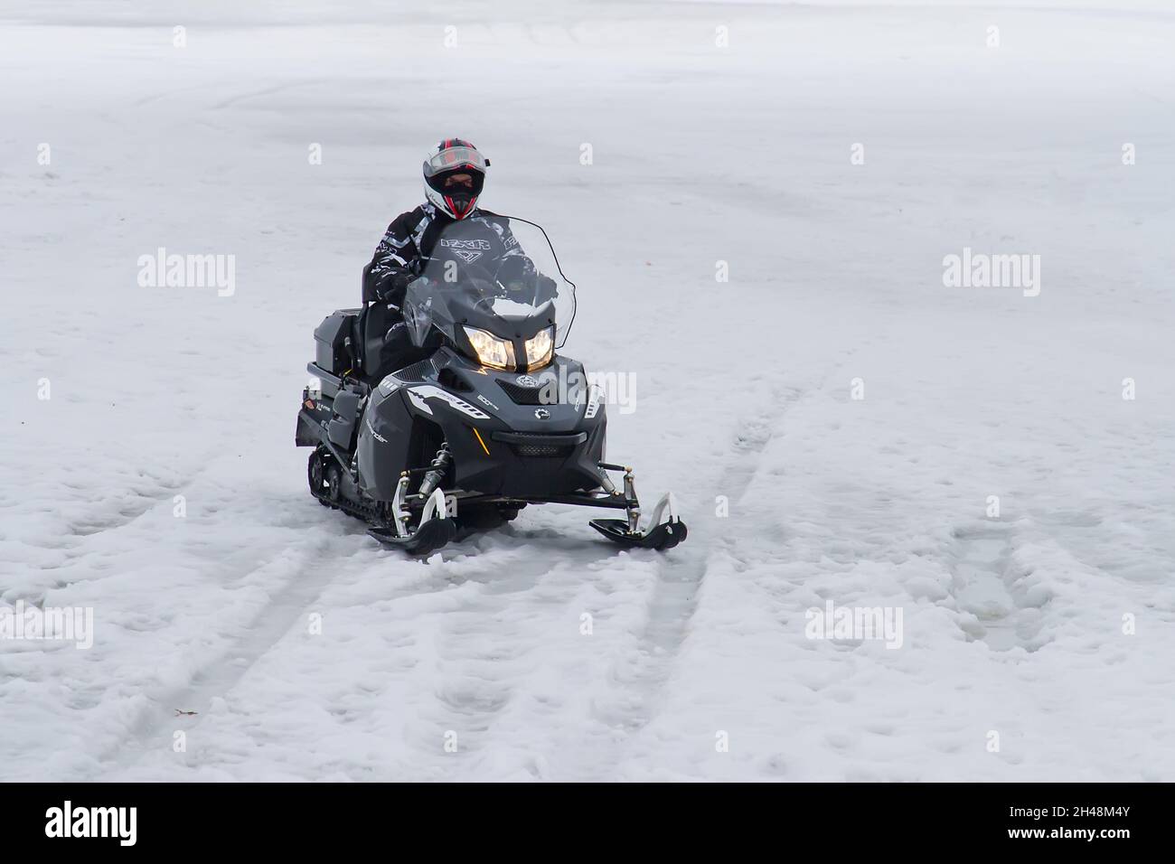 22.02.2014. Russland. Region Moskau. Transport von Fahrzeugen. Ein Mann auf einem Schneemobil bewegt sich auf dem Eis. Stockfoto