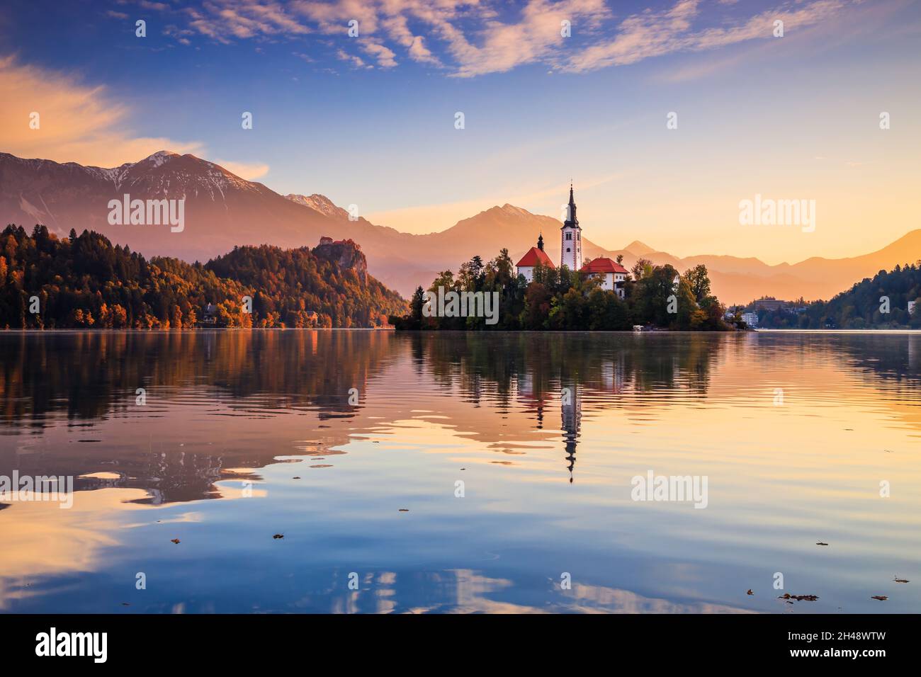Bleder See, Slowenien. Sonnenaufgang am Bleder See mit der berühmten Insel Bled und dem historischen Schloss Bled im Hintergrund. Stockfoto