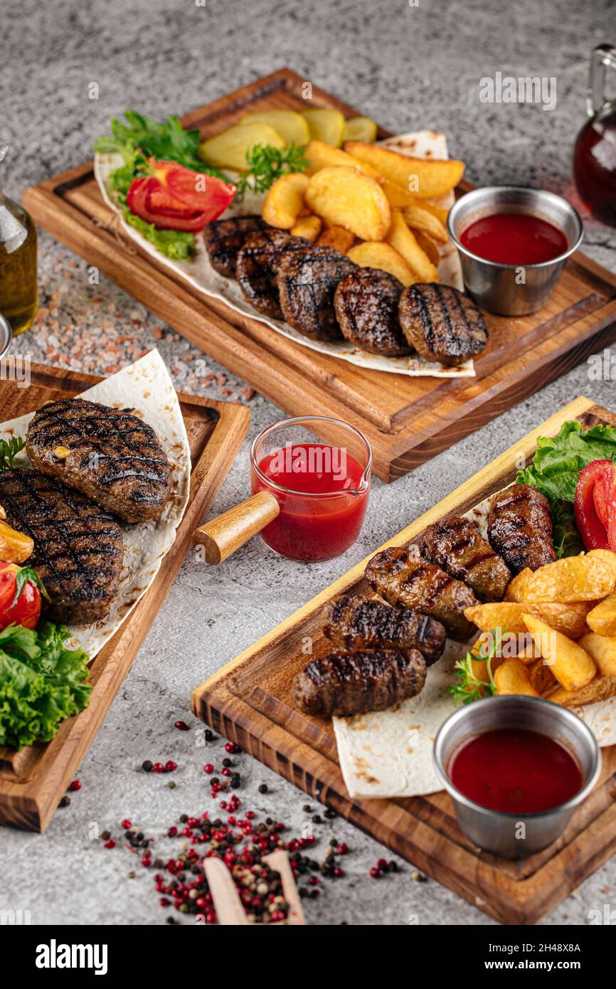 Verschiedene gegrillte Rindersteaks mit Sauce und Garnitur Stockfoto