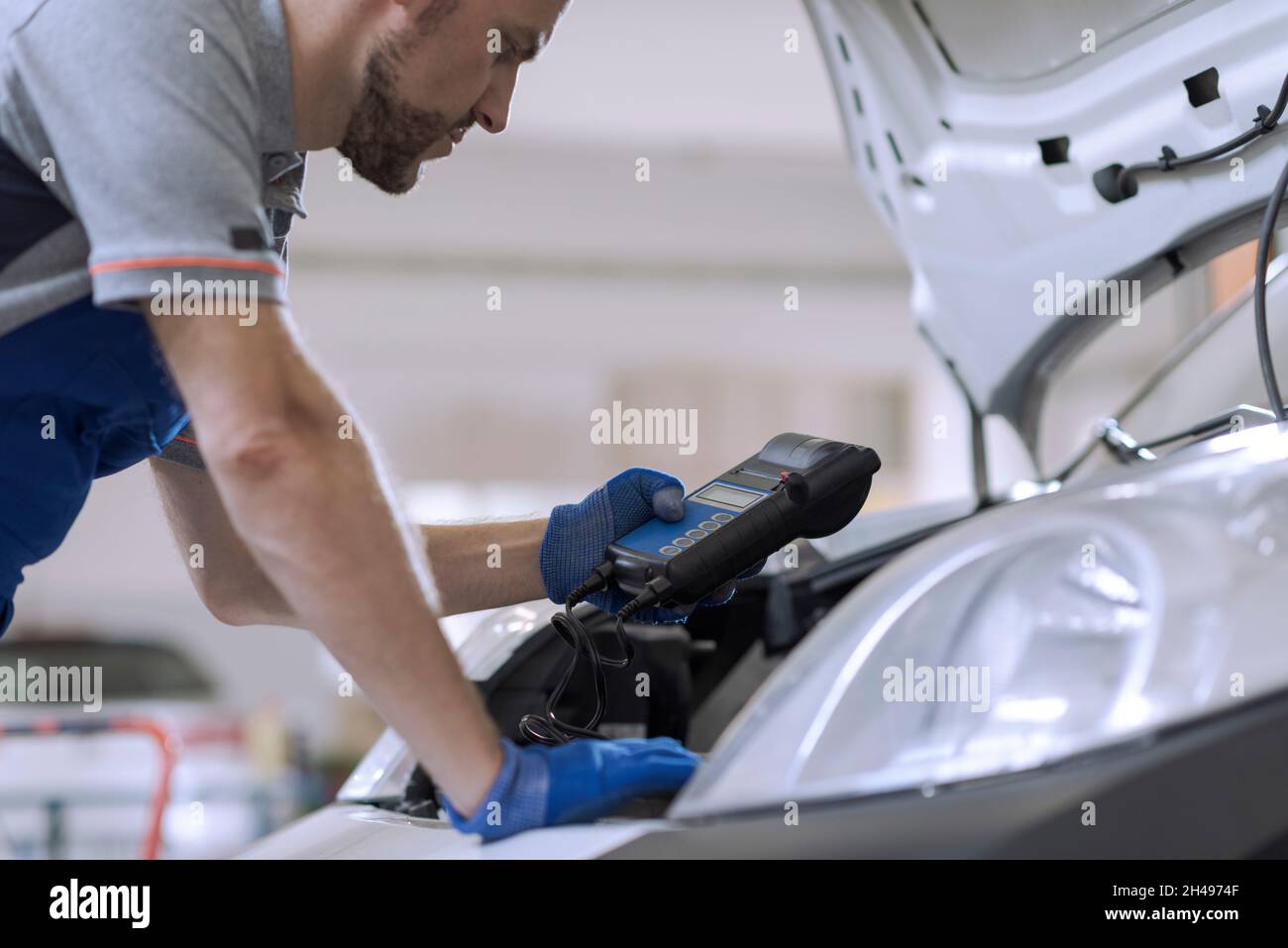 Professioneller Mechaniker, der eine Autoinspektion macht, verwendet einen Batterietester Stockfoto