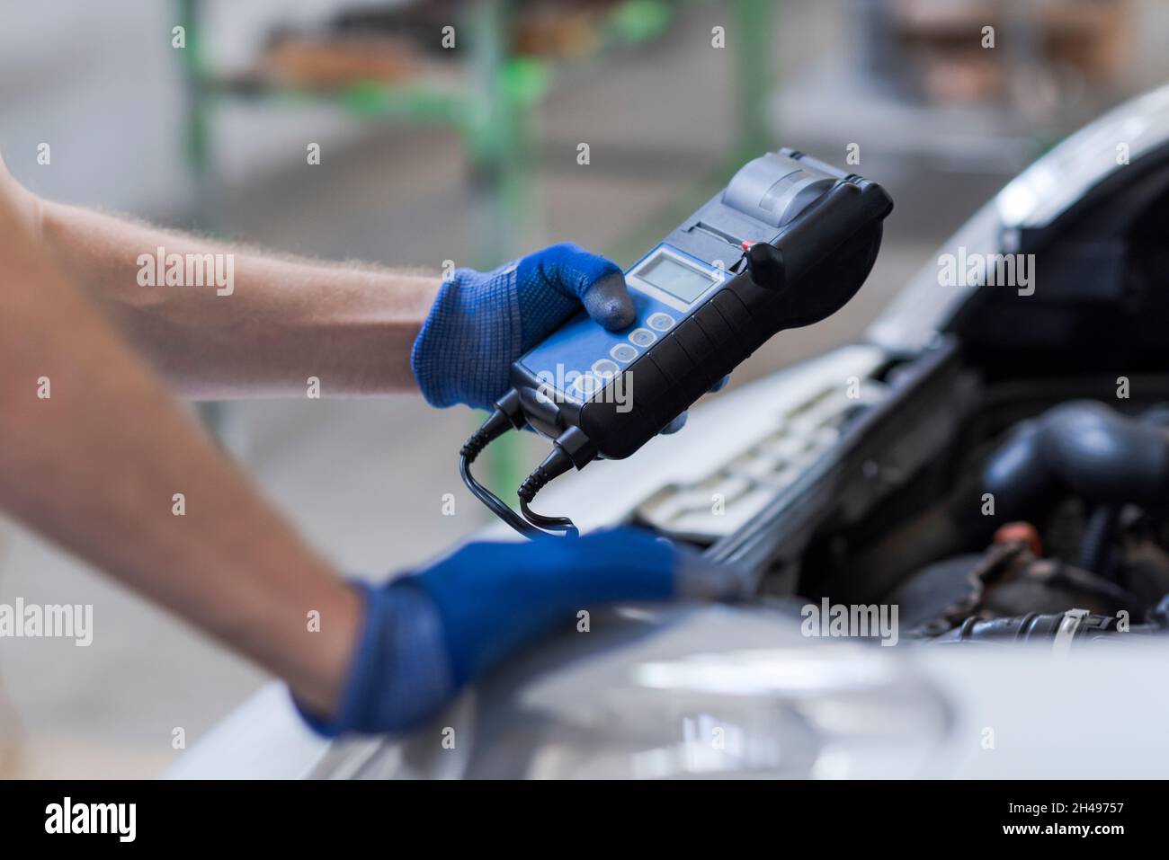 Professioneller Mechaniker, der eine Autoinspektion macht, verwendet einen Batterietester Stockfoto