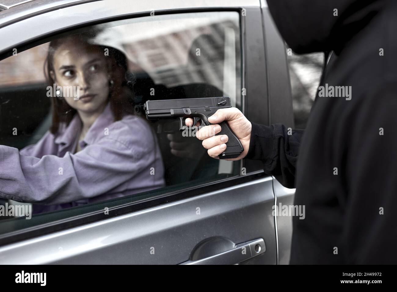 Ein Mann, der einen Räuber mit Handfeuerwaffe hält, um einen Gangster zu entführen, um einen Geiselfahrer zu entführen, der schockiert und gefährlich auf dem Konzept der Gewalt auf der Straße ist. Seitenansicht auf f Stockfoto