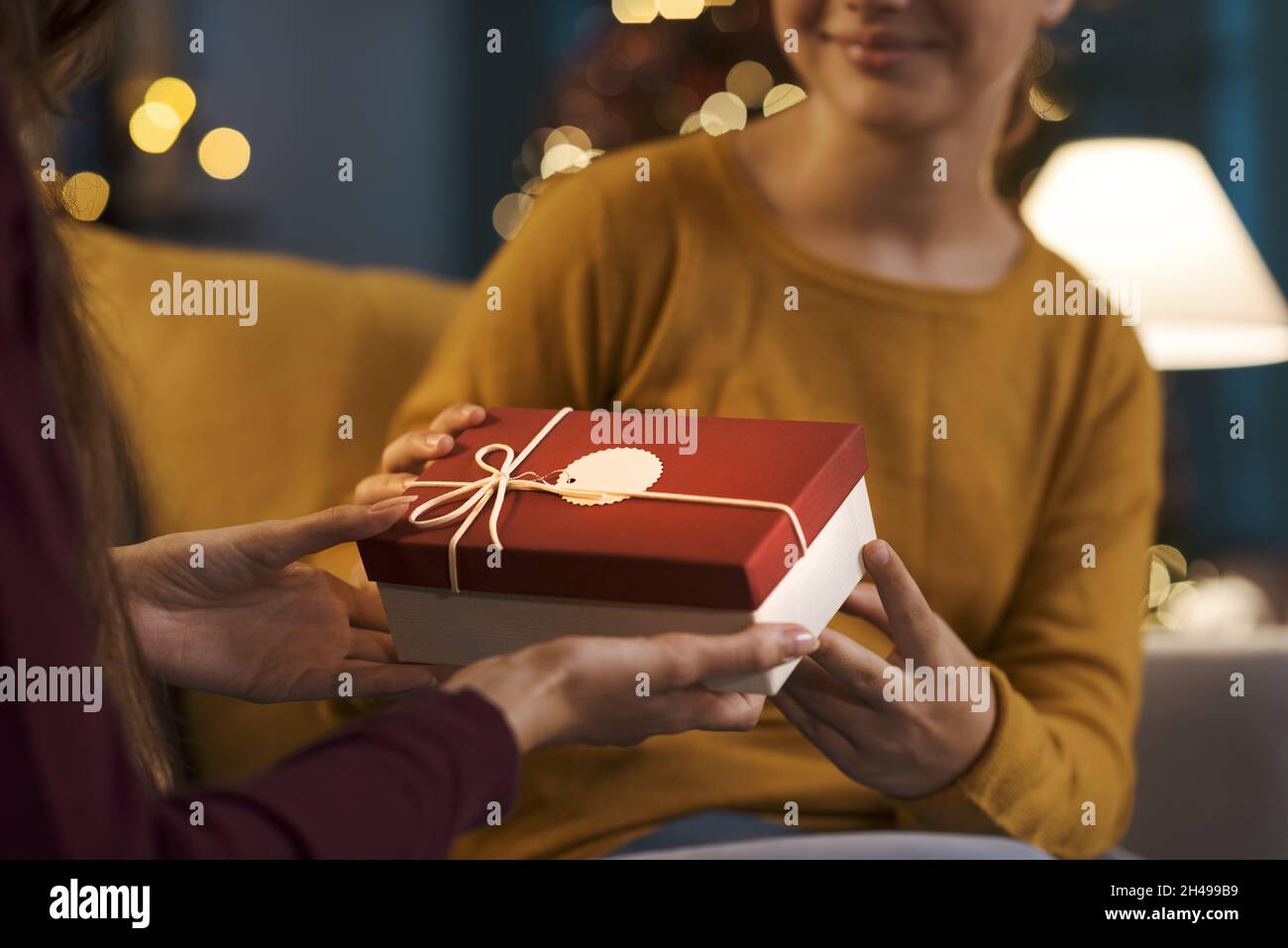 Glückliches Mädchen erhält ein schönes Weihnachtsgeschenk von ihrer Mutter Stockfoto