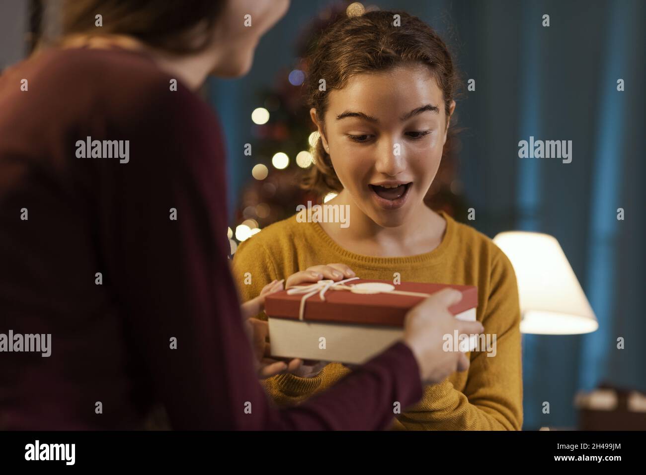Glückliches Mädchen erhält ein schönes Weihnachtsgeschenk von ihrer Mutter Stockfoto