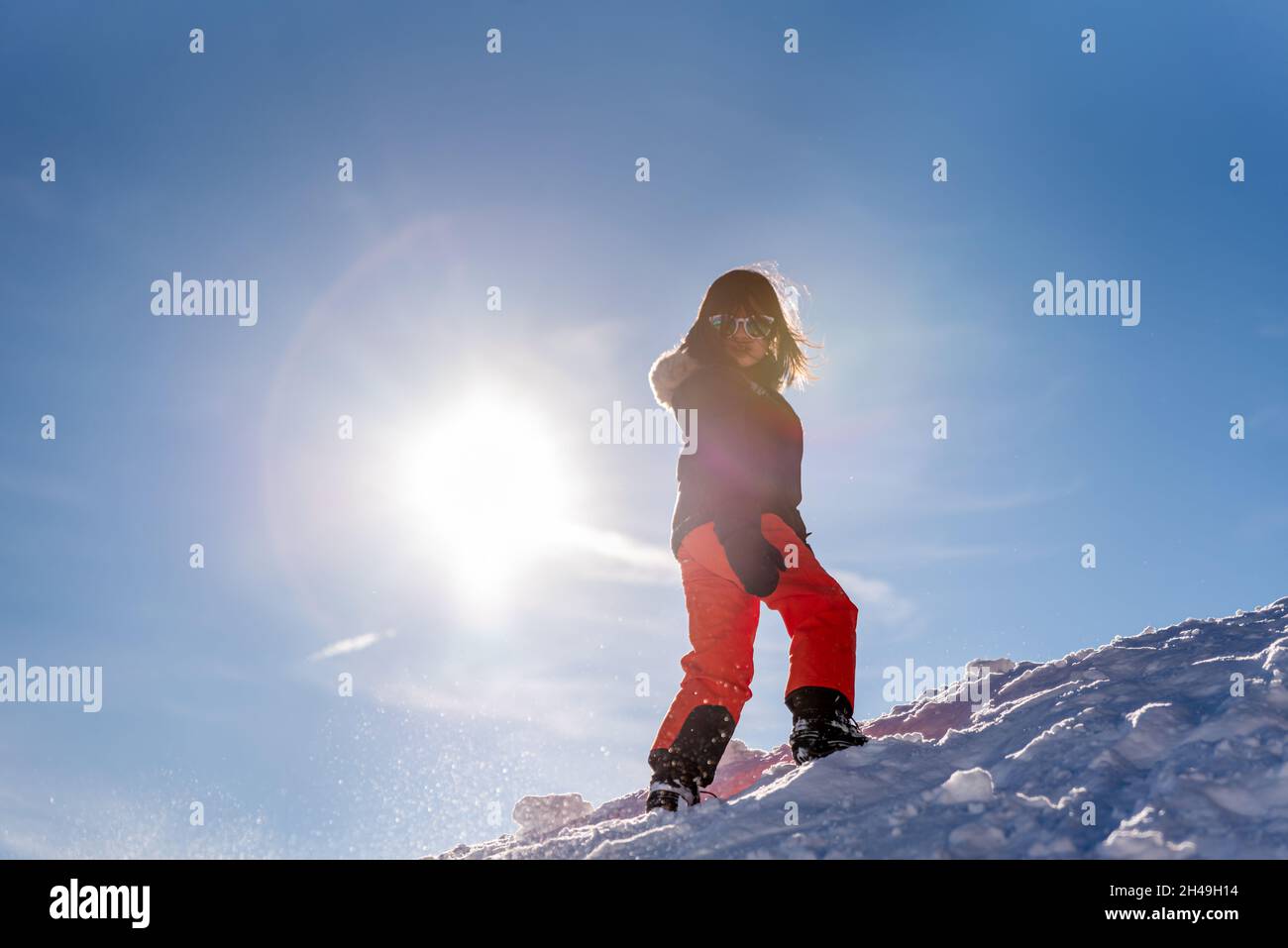 Kind läuft im Schnee. Ein asiatisches Mädchen in Skibekleidung und Handschuhen, die im Winter spielen. Frohe Kindheit. Stockfoto