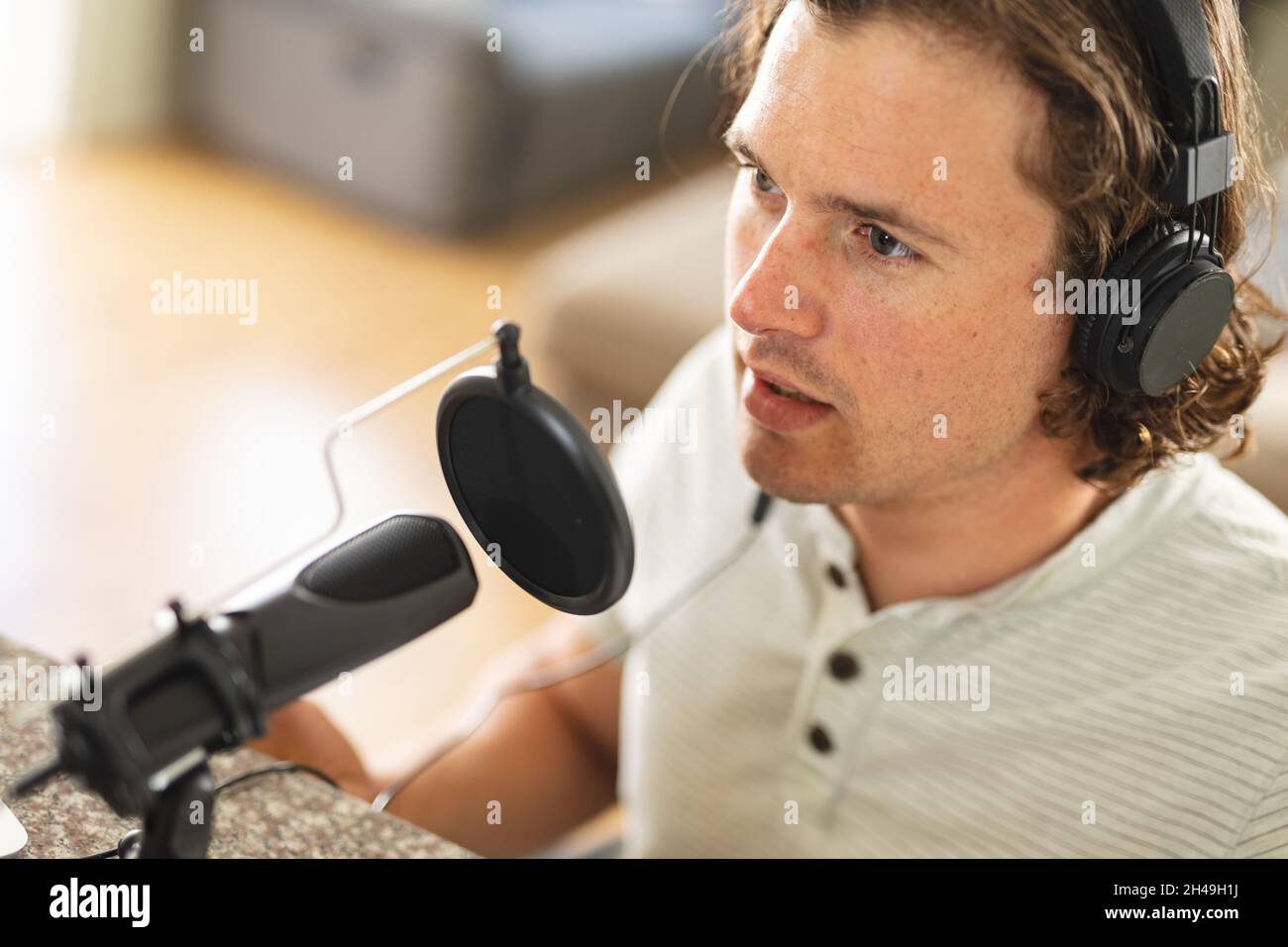 Kaukasischer behinderter Mann, der Podcast mit einem Mikrofon aufzeichnet, das zu Hause sitzt Stockfoto