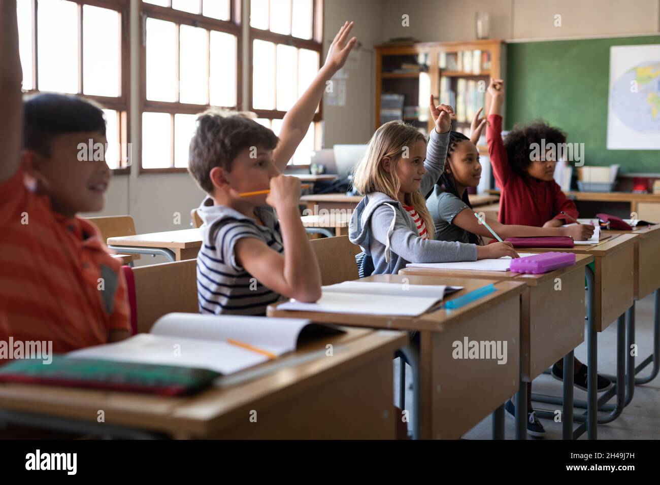 Eine Gruppe von multiethnischen Kindern, die in der Schule auf ihrem Schreibtisch sitzen. Grundschulbildung Stockfoto