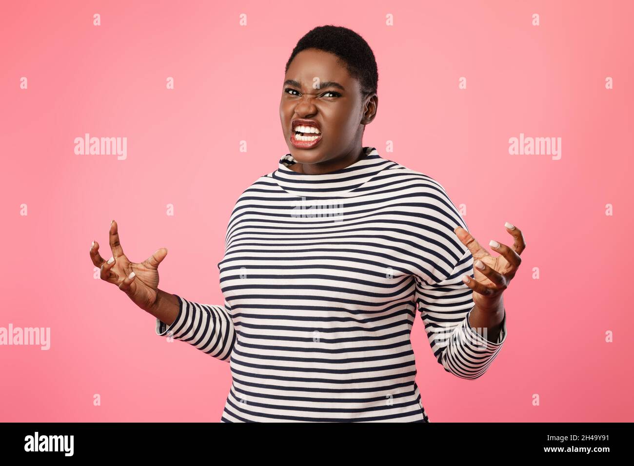 Wut. Angry Plus Size African American Lady Drückt Aggression Beim Blick Auf Kamera Posiert Im Studio Über Rosa Hintergrund Stehen. Negative Emotionen Stockfoto