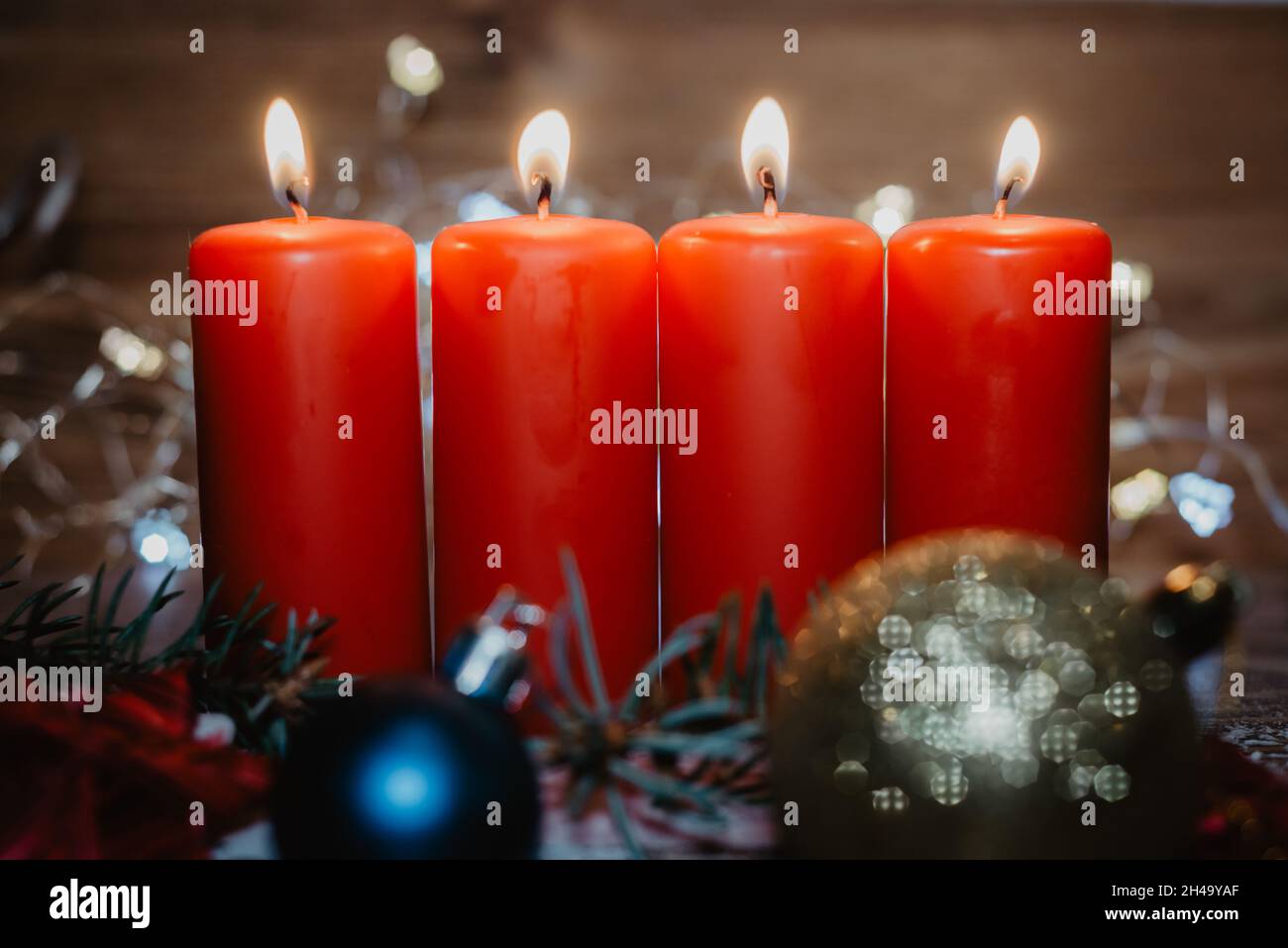 Vier rote Adventskerzen mit vier Kerzen angezündet und weihnachtsdekoration im Schnee als Vorlage Stockfoto