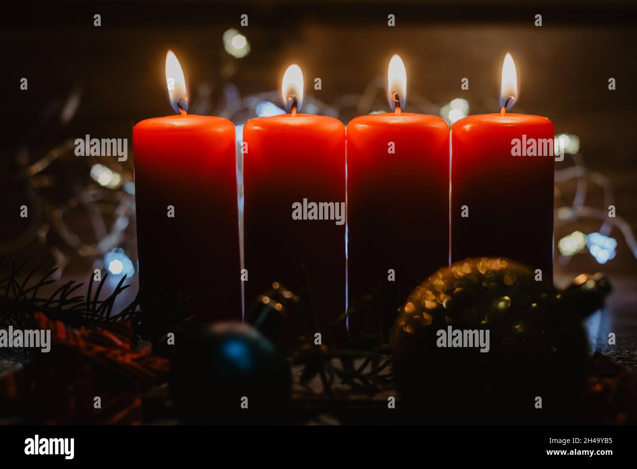 Vier rote Adventskerzen mit vier Kerzen angezündet und weihnachtsdekoration im Schnee als Vorlage Stockfoto