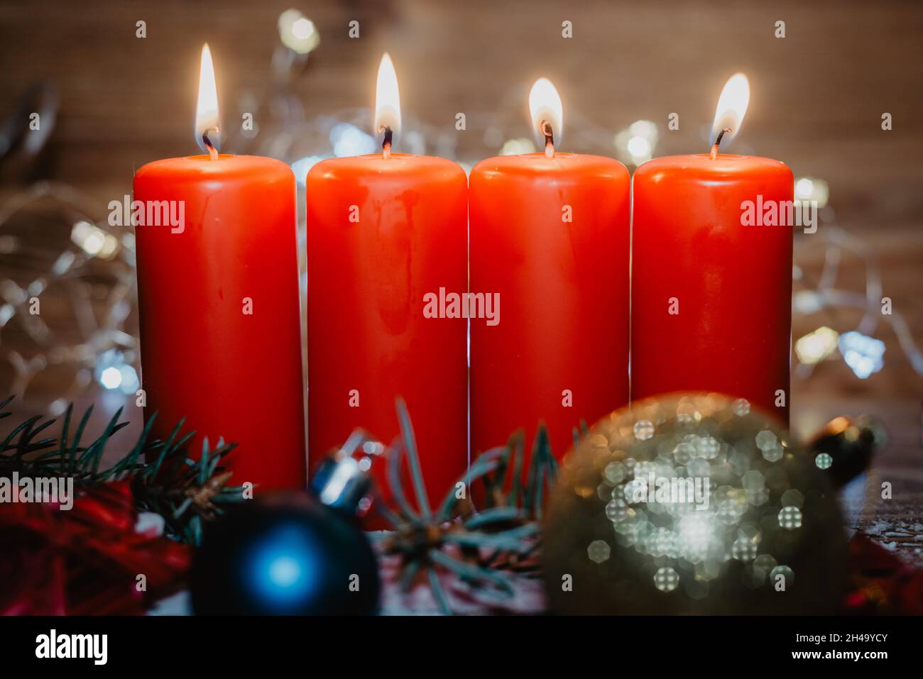 Vier rote Adventskerzen mit vier Kerzen angezündet und weihnachtsdekoration im Schnee als Vorlage Stockfoto
