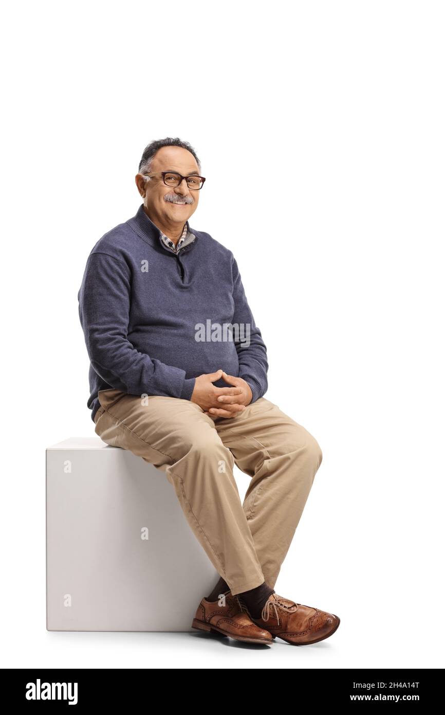 Reifer Casual Mann sitzt auf einem weißen Würfel isoliert auf weißem Hintergrund Stockfoto