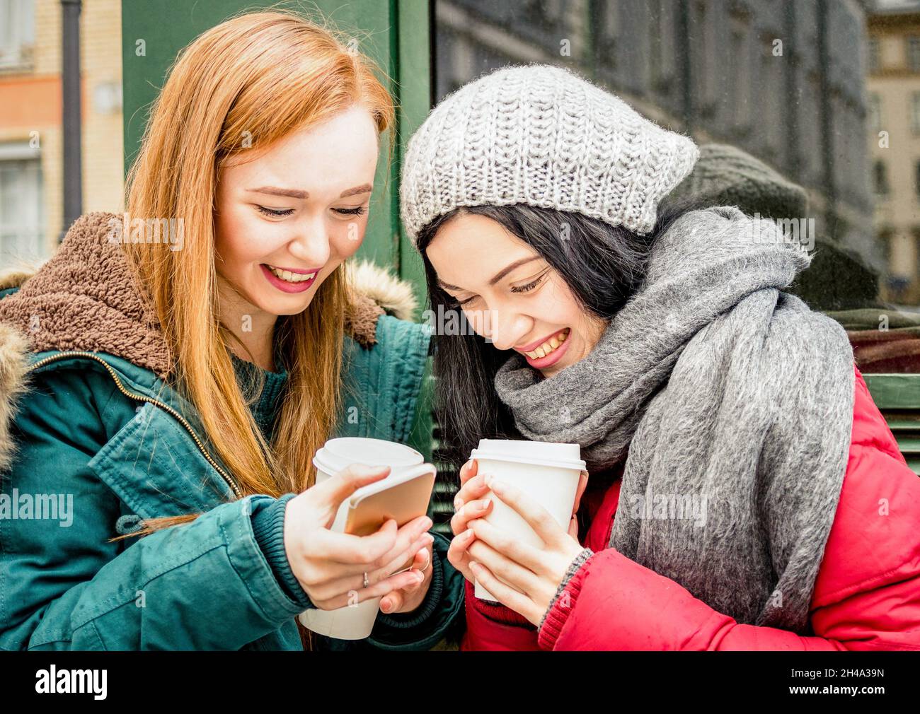 Glückliche Freundinnen beste Freundin mit Spaß mit Kaffee Take Away Tasse in der Herbstsaison - Freundschaftskonzept mit fröhlichen Mädchen, die Zeit miteinander teilen Stockfoto
