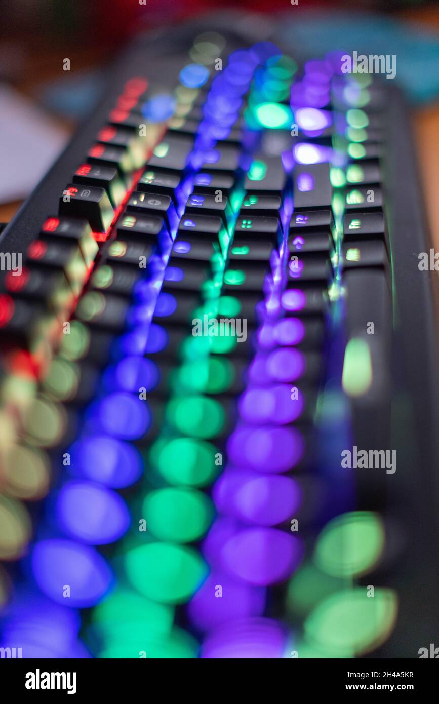 Flacher Fokus des mittleren Teils einer RGB-Gaming-Tastatur mit seinen bunten Lichtern Stockfoto
